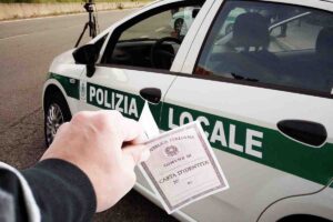 Carta d'identità ed un'auto della Polizia Locale