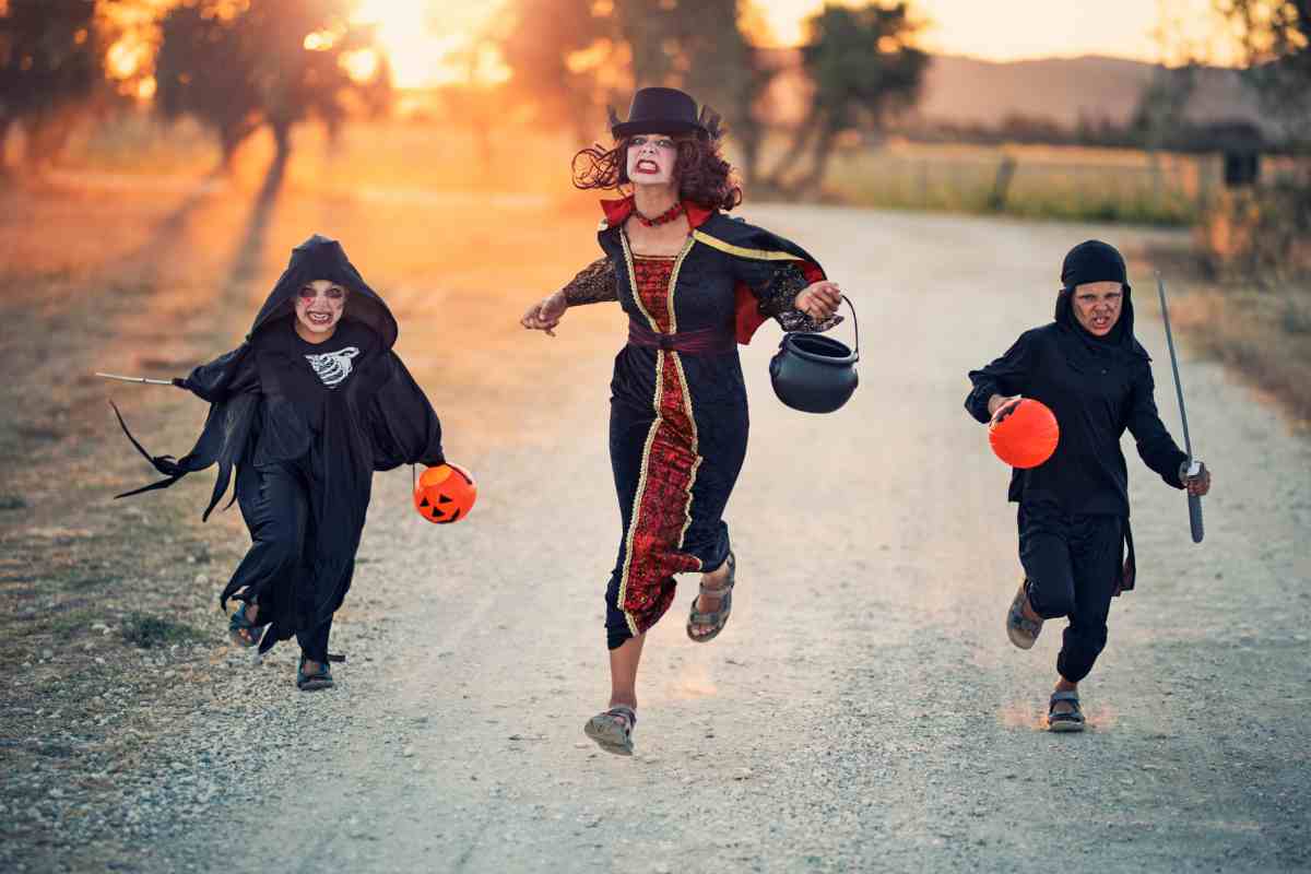 bambini e signora corrono per strada ad halloween