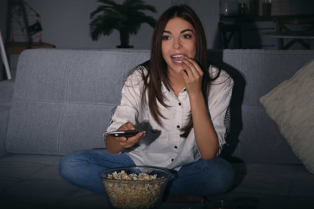 ragazza guarda tv e mangia popcorn