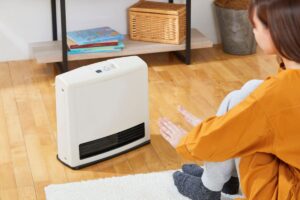 donna che si riscalda davanti stufa elettrica