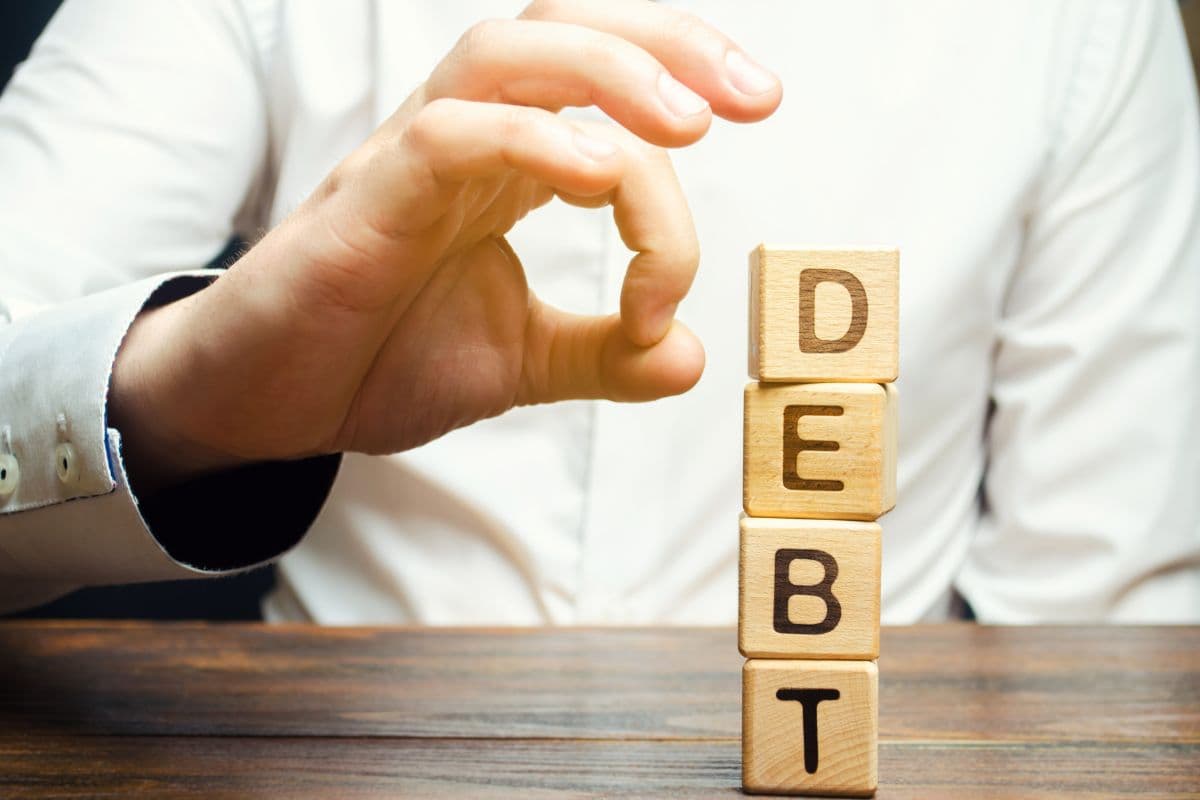 dita di uomo che scacciano caselle che formano parola debt