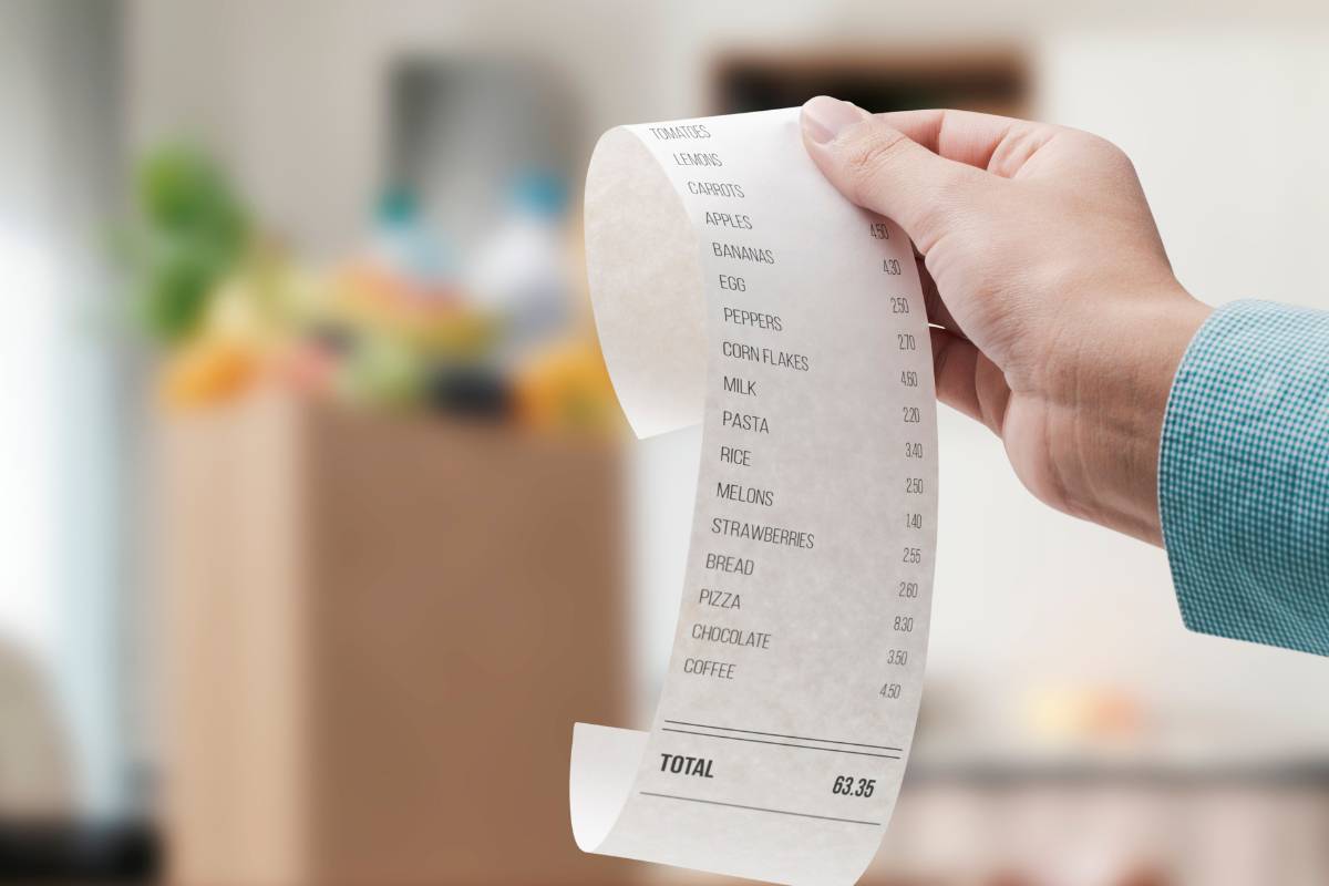 mano scontrino sullo sfondo busta della spesa