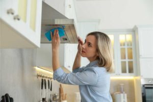 Donna che pulisce la cappa della cucina